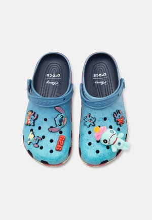 Niebieskie Crocsy z zawieszkami tematycznymi Disney Stitch, w tym postaciami, czerwoną "626" oraz pluszową lalką na prawej nucie, z regulowanymi paskami na piętę.