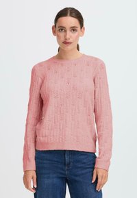 Pullover lavorato a maglia rosa chiaro con un motivo a trama e dettagli a traforo, scollatura rotonda e maniche lunghe. Orlo orizzontale a costine.