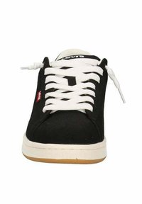 Sneaker nera con lacci bianchi, tomaia in tela, suola in gomma e un piccolo etichetta rossa. Presenta una punta arrotondata e una superficie texturizzata.