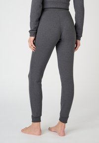 Pantalones de chándal gris oscuro hechos de tela suave. Diseño ajustado con puños acanalados y una cintura lisa, con costuras planas a lo largo de los lados.