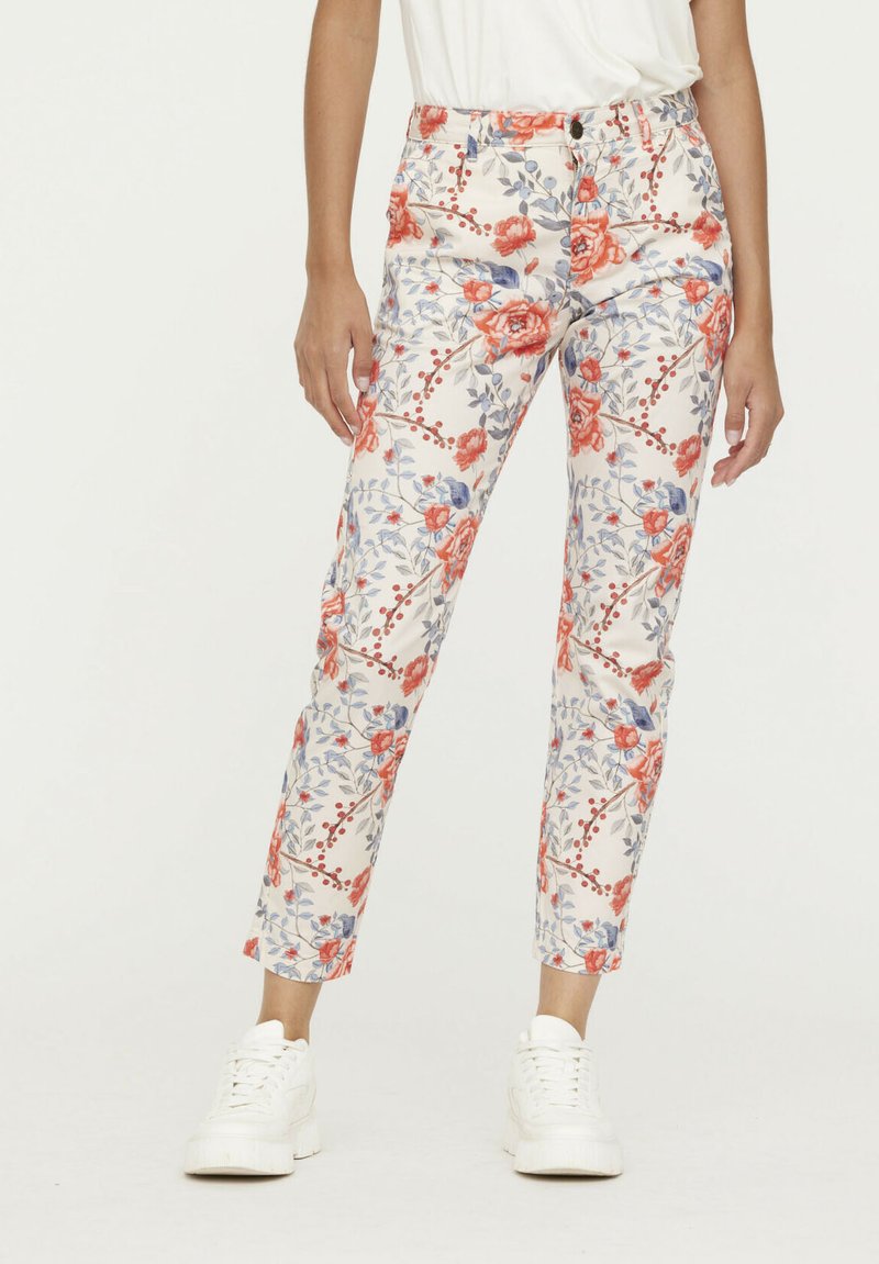 Pantalons floraux blancs avec des motifs de fleurs rouges et bleues, présentant une coupe ajustée, des passants de ceinture et une fermeture à bouton à l'avant.