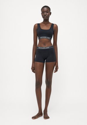 Svart idrottsbh och högmidjade shorts med ett kontrasterande elastiskt band som har texten "POLO RALPH LAUREN". Slät, elastisk tyg.