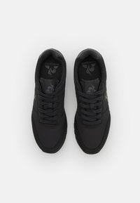 Scarpe sportive nere con una superficie sintetica liscia, punta arrotondata e design con lacci. Presentano una soletta testurizzata e un branding discreto.