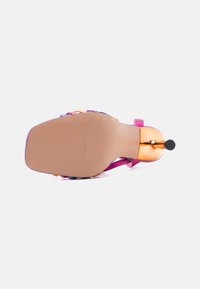 Μονόπλευρη όψη ψηλοτάκουνου σανδάλιου με τετράγωνη μύτη, ροζ και πορτοκαλί λουριά, και μεταλλικό τακούνι στιλέτο σε ροζ χρυσό πάνω σε λευκό φόντο.