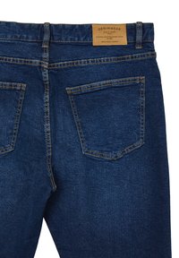 Jeans in denim blu scuro con una finitura testurizzata, dotati di due tasche posteriori e di un'etichetta in pelle sulla vita. Dettagli di cucitura a contrasto.