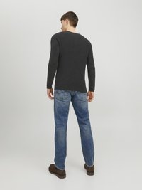Maglione lavorato a maglia grigio scuro a maniche lunghe con scollatura rotonda, abbinato a jeans in denim blu e stivali marroni. La vestibilità è rilassata e casual.