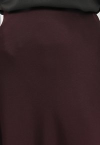 Gonna a matita bordeaux realizzata in tessuto morbido, caratterizzata da una silhouette snella e una vita sartoriale per una forma aderente.
