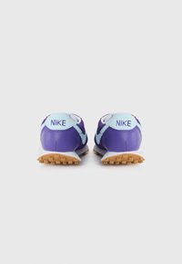 Paarse Nike-schoenen met lichtblauwe accenten, voorzien van een textiel bovenzijde, gevoerd kraag en een gestructureerde rubberen zool.