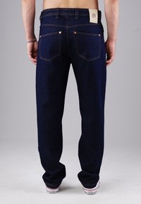 Dunkelblaue Denim-Jeans mit geradem Bein, ausgestattet mit gesteppten Gesäßtaschen und einem braunen Lederpatch am Bund.