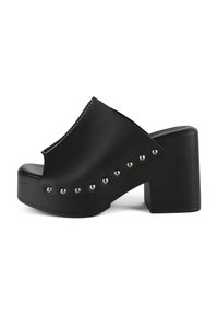 Black platform clog with a rounded toe, featuring a smooth upper, silver stud accents along the side, and a textured block heel.