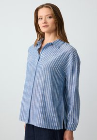 Blue and white striped shirt made of lightweight fabric. Features a button-up front, a classic collar, and loose fit with long sleeves.