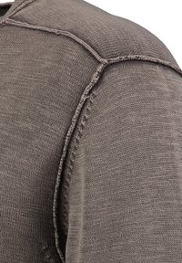 Gebreide kleding in een gedempte bruintint met een gladde textuur. Heeft subtiele stiksels langs de schoudernaden en een getailleerd ontwerp.