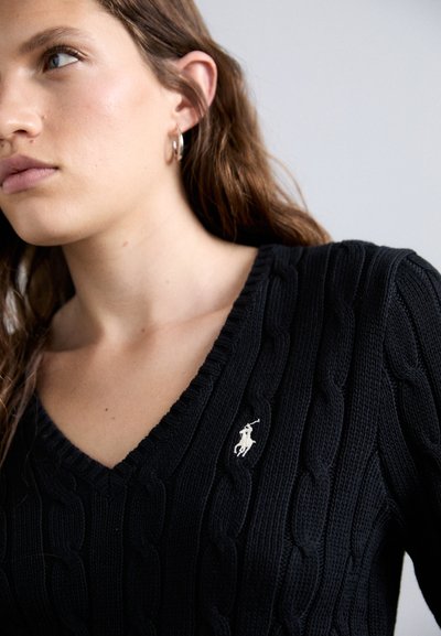Black cable-knit sweater with a V-neckline and a small white embroidered logo on the chest. Features textured pattern and ribbed edges.