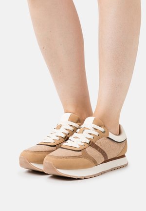 Zapatillas beige con parte superior de ante y textil, cordones blancos, panel texturizado y suela de goma. Diseño de corte bajo con detalles sencillos.