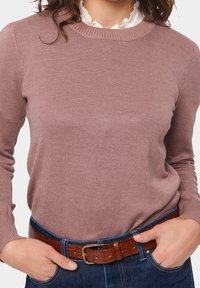 Light pink knitted sweater with a round neckline, slim fit, and ribbed cuffs, paired with a brown leather belt and blue denim jeans.