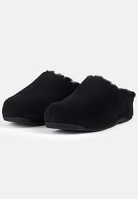 Black slippers made of soft suede material, featuring a rounded shape, and a fuzzy trim along the opening. Textured black soles.