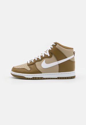 Baskets montantes en cuir beige et marron avec lacets blancs et logo Nike swoosh blanc sur le côté.
