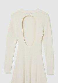 Abito in maglia color crema con maniche lunghe, scollatura profonda sulla schiena e texture a coste. Gonna svasata dalla vita, con una finitura in tessuto morbido.