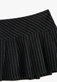 Sort plisseret nederdel med hvide striber, der har en struktureret talje og tekstureret stof, der fremhæver et dynamisk lagdelt design.