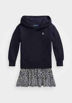 Marineblaues Kapuzensweatshirt-Kleid mit Fronttasche und kleinem weißem Logo über dem schwarz-weiß blumengemusterten Rüschenrocksaum.