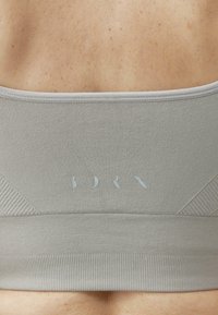Lichtgrijs sport crop top met textuur, smalle bandjes en subtiele branding op de achterkant. Ontworpen voor comfort en pasvorm.