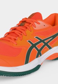 Φωτεινό πορτοκαλί αθλητικό παπούτσι Asics με πράσινο λογότυπο, πορτοκαλί κορδόνια, διχτυωτό επάνω μέρος και λευκή μεσαία σόλα με πράσινα στοιχεία στην εξωτερική σόλα.