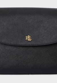 Musta teksturoitu clutch-laukku kiiltävällä pinnalla, jossa on kultainen logo-aksentti edessä ja magneettinen läppäkiinnitys.