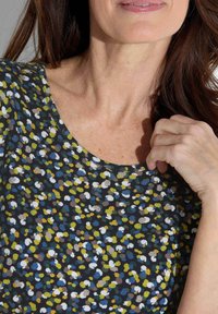 Bloemmotief bovenstuk in donkere kleuren met groene, blauwe en witte stippen. Ronde halslijn van zacht materiaal en een ontspannen pasvorm.