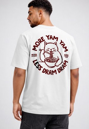 Man wearing white t-shirt with red cat eating noodles and text "More Yam Yam Less Dram Dram" on the back.