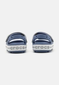 Mėlyni guminių sandalai su pilku užnugariu ir balta padais. Ant kulno iškilmingai išspaustas logotipas "crocs". Tekstūruota pado ir išorinio pado dalis.