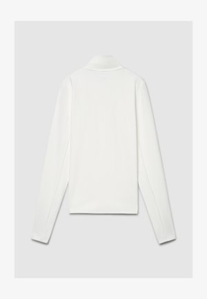 Polo blanc à manches longues avec col plat, texture lisse, fentes latérales et marquage minimal au dos. Coupe et design uniformes.