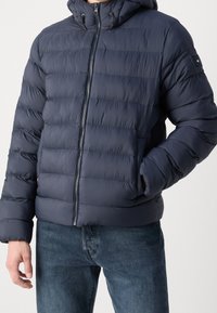 Navy puffer jacket with a hood, quilted design, front zipper, elastic cuffs, and side pockets. Made of lightweight, water-resistant material.