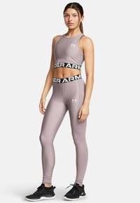 Vala mauve urheilupolet ja matching leggingit, joissa on musta Under Armour -logo nauha. Tiukka muotoilu, sileä pinta ja yhdistetty mustiin urheilujalkineisiin.