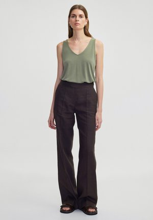 Top sin mangas en verde oliva con escote en V, combinado con pantalones marrones de tiro alto y pierna ancha, que presentan sutiles rayas verticales, y sandalias tipo easy-on.