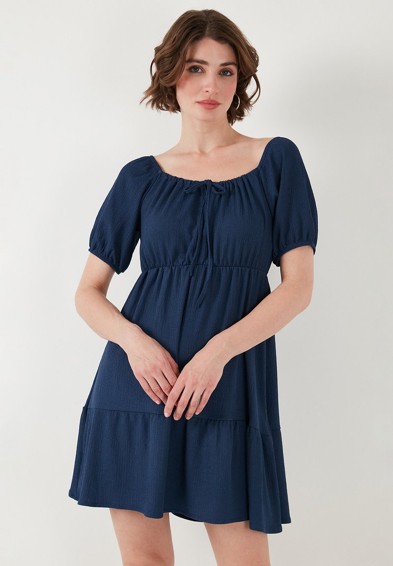 Navy blue short-sleeve dress with a square neckline, tie detail at the front, and a tiered skirt. Fabric has a textured finish.