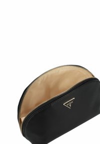 Zwarte ritstas voor cosmetica met een ronde vorm, gladde buitenkant en gouden hardware. De binnenkant is beige met een logo-patroon.