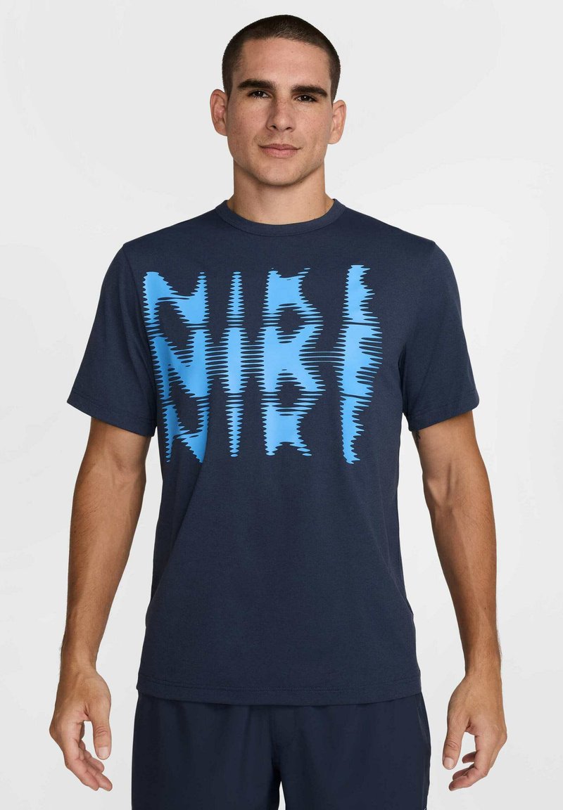 Navy blue cotton t-shirt featuring a prominent light blue zigzag pattern text across the front. Short sleeves and round neck design.