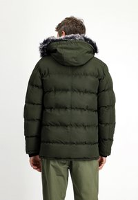 Olijfgroene pufferjack met een capuchon, voorzien van een nepbontafwerking en een gequilt ontwerp. Glad oppervlak, zichtbare stiksels en elastische manchetten.