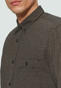 Dunkles, strukturiertes Hemd mit Button-Down-Kragen, Brusttasche und schwarzen Knöpfen. Es zeichnet sich durch einen gewebten Stoff im Fischgrätmuster aus.