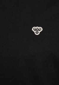 Sort stof med et lille hvidt broderet bi-logo centreret på det øvre brystområde.