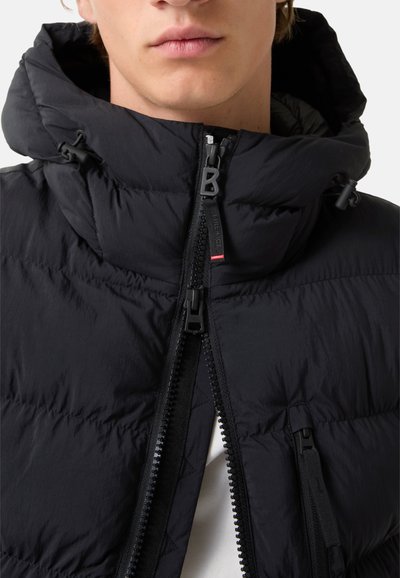 Černá péřovka s kapucí, vybavená plným zipem vpředu, texturovanou tkaninou a elastickými šňůrkami pro nastavení kapuce.