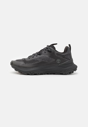 Zapatilla deportiva negra con parte superior de malla transpirable, acentos texturizados, suela de goma resistente y talón reforzado para mayor soporte.