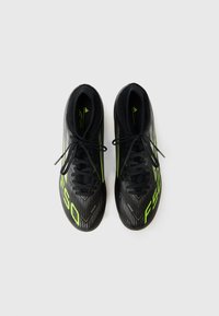 Zwarte voetbalschoenen met groene accenten en veters, met een textuurdesign, weergegeven op een neutrale achtergrond.