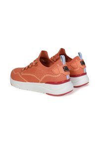 Baskets tricotées orange avec semelles blanches, comportant des accents rouges, bout arrondi et marque bien visible au niveau du talon. Conception à lacets pour un maintien sécurisé.