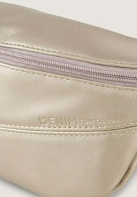 Metaliczna złota saszetka wykonana z syntetycznego materiału o gładkiej fakturze, z zapięciem na zamek oraz wytłoczonym logo "DENIM TOM TAILOR".