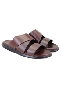 Sandales en cuir marron avec un design de lanières croisées, semelle plate et détails texturés minimaux. Présente des bords arrondis et une construction flexible.