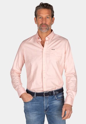 Lichtroze overhemd met lange mouwen en knopen, voorzien van een borstzakje en een subtiele textuur, gecombineerd met blauwe denim jeans en een donkere gevlochten riem.