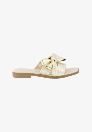 Sandal in metallo dorato con un ampio design a fiocco sulla parte superiore, suola piatta e soletta testurizzata. Finitura in pelle liscia.