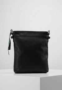 Czarna skórzana torba na ramię o gładkiej fakturze, pionowym kształcie, zamknięciu u góry oraz metalowych ozdobach. Posiada dekoracyjną metkę.