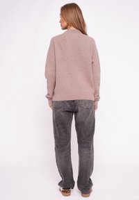 Jasnoróżowy dzianinowy sweter z okrągłym dekoltem, luźny krój. Połączony z wyblakłymi szarymi dżinsami o szerokich nogawkach i brązowymi butami z panterkowym akcentem.